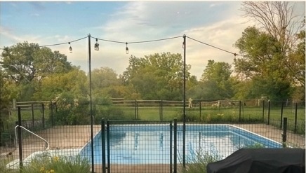 Backyard pool at Bacon Acres at dusk with string lights