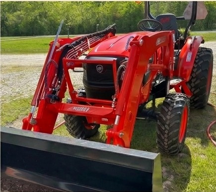 Red Kubota tractor with front loader parked in the yard